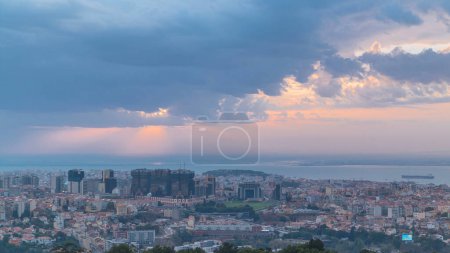 Panoramic sunrise view over Lisbon and Almada from a viewpoint in Monsanto at morning timelapse. Aerial top overview with colorful clouds and rays of light