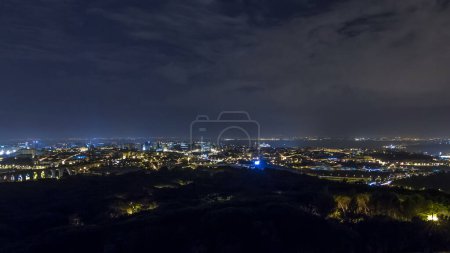 Panoramic overview of Lisbon and Almada from a viewpoint in Monsanto night timelapse. Aerial top view with traffic on illuminated city streets