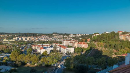 Photo for Beautiful cityscape overview of Leiria early morning, Portugal. Aerial top view with green trees, blue sky and moving shadows - Royalty Free Image