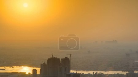 Téléchargez les photos : Lever de soleil avec paysage urbain d'Ajman depuis le ciel sur le toit. Site de construction et ciel orange. Ajman est la capitale de l'émirat d'Ajman aux Émirats arabes unis. - en image libre de droit