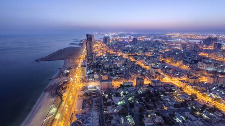 Stadtbild von Ajman vom Dach aus von der Nacht zum Tag Übergang Zeitraffer vor Sonnenaufgang. Ajman ist die Hauptstadt des Emirats Ajman in den Vereinigten Arabischen Emiraten.