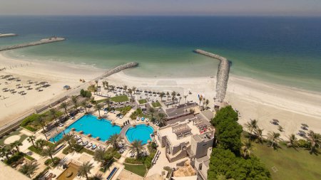 Beautiful area of beach in Ajman timelapse near the turquoise waters of Arabian Gulf, UAE. Panoramic rooftop view with swimming pool. Sea shore and port