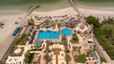 Foto de Hermosa zona de playa en Ajman timelapse cerca de las aguas turquesas del Golfo Arábigo, Emiratos Árabes Unidos. Vista panorámica de la azotea con piscina - Imagen libre de derechos