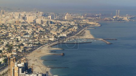 Foto de Vista panorámica de la costa de Sharjah desde la azotea de Ajman, la tercera ciudad más grande y poblada de los Emiratos Árabes Unidos. Sharjah se encuentra a lo largo de la costa norte del Golfo Pérsico en la Península Arábiga - Imagen libre de derechos