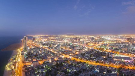 Téléchargez les photos : Paysage urbain d'Ajman depuis le toit du jour jusqu'à la quasi-transition chronométrage panoramique aérien après le coucher du soleil. Ajman est la capitale de l'émirat d'Ajman aux Émirats arabes unis. - en image libre de droit