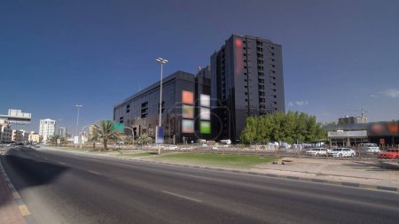 Téléchargez les photos : Paysage urbain d'Ajman avec la circulation sur la route avec bâtiment noir du centre commercial et hôtel hyperlapse timelapse panoramique. Ajman est la capitale de l'émirat d'Ajman aux Émirats arabes unis. - en image libre de droit