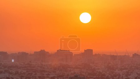 Téléchargez les photos : Coucher de soleil à Ajman vue aérienne depuis le timelapse sur le toit. Vue du soir du grand soleil sur ciel orange aux Émirats arabes unis. - en image libre de droit