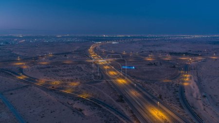 Photo for Highway roads in desert with traffic night to day transition timelapse in a big city from Ajman to Dubai before sunrise. Transportation concept. Aerial view from top - Royalty Free Image
