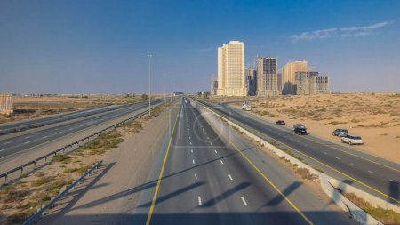 Photo for Highway roads in desert with traffic timelapse in a big city from Ajman to Dubai before sunset from bridge. Transportation concept. View from top - Royalty Free Image
