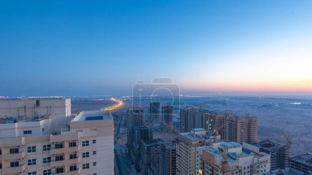 Téléchargez les photos : Paysage urbain d'Ajman du toit de la nuit au jour transition timelapse. Vue sur la nouvelle construction du quartier. Ajman est la capitale de l'émirat d'Ajman aux Émirats arabes unis - en image libre de droit
