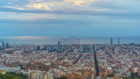 Barcelonas Morgendämmerung: Sonnenaufgang im Zeitraffer von den Bunkern des Carmel in Spanien aus. Luftaufnahme von oben, Lichtstrahlen durchdringen Wolken, malen das Stadtbild mit leuchtenden Farben vor einem bunten Morgenhimmel