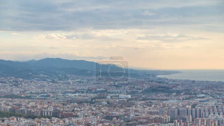 Foto de Panorama de Barcelona durante el amanecer timelapse, España, visto desde los bunkers del Carmelo en una mañana nublada con rayos de luz. Vista aérea desde la colina con montañas. Cielo colorido - Imagen libre de derechos