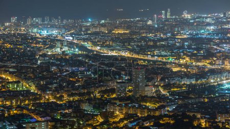 Barcelona and Badalona skyline with roofs of houses and traffic at night timelapse. Aerial view from Iberic Puig Castellar Village viewpoint on top of hill