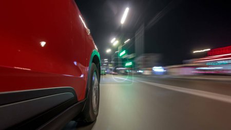Photo for Drivelapse urban look from fast driving car at a night avenue in a city timelapse hyperlapse, road with lights reflected on car at high speed. Rapid rhythm of a modern city. Blurred motion - Royalty Free Image