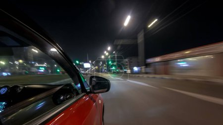 Téléchargez les photos : Drivelapse look urbain de la voiture de conduite rapide sur une avenue de nuit dans une ville timelapse hyperlapse, route avec des lumières réfléchies sur la voiture à grande vitesse. Rythme rapide d'une ville moderne. Mouvement flou - en image libre de droit