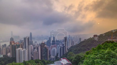 Foto de La famosa vista panorámica de Hong Kong desde el timelapse de Victoria Peak. Tomado al amanecer mientras el sol sube sobre la bahía de Kowloon. Muchos edificios de gran altura desde arriba - Imagen libre de derechos