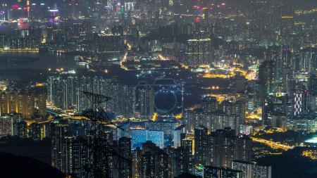 Téléchargez les photos : Vue aérienne depuis Fei ngo shan Kowloon Peak night timelapse Hong Kong ville skyline. Grands bâtiments éclairés et lignes de transport d'électricité d'en haut - en image libre de droit