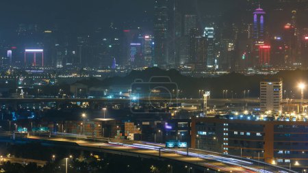 Téléchargez les photos : Hong Kong Skyline près de Container Terminal Nuit timelapse aérienne - Kwai Tsing Container Terminals est l'un des ports les plus achalandés au monde. Trafic sur l'autoroute et grands gratte-ciel. - en image libre de droit