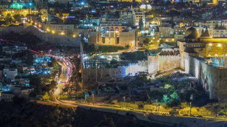 Foto de Vista de cerca a Jerusalén cerca de al-aqsa timelapse noche con el tráfico en la carretera desde el Monte de los Olivos. Vista superior con edificios iluminados y pared - Imagen libre de derechos