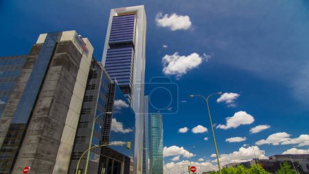 Téléchargez les photos : Skyscrapers timelapse hyperlapse dans le quartier d'affaires Four Towers avec les plus hauts gratte-ciel de Madrid et d'Espagne. Quartier de bureaux avec trafic à l'intersection - en image libre de droit