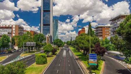 Téléchargez les photos : Skyscrapers Timelapse dans le quartier d'affaires Four Towers avec les gratte-ciel les plus hauts de Madrid et d'Espagne. Quartier de bureaux avec circulation sur la rue depuis le pont - en image libre de droit