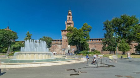 Téléchargez les photos : Entrée principale du château de Sforza - Castello Sforzesco et fontaine devant lui hyperlapse timelapse, Milan, Italie. Ciel bleu le jour d'été. Des gens qui marchent - en image libre de droit