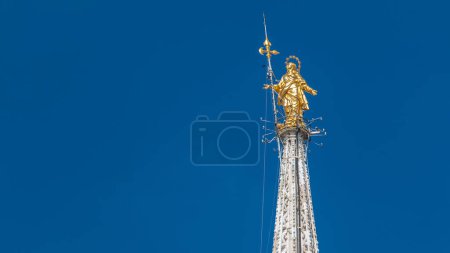 Photo for The Madonnina atop Milan Cathedral timelapse in Milan, Italy. Close up view. Blue cloudy sky at summer day. This statue was erected in 1762 at the height of 108.5 m. - Royalty Free Image