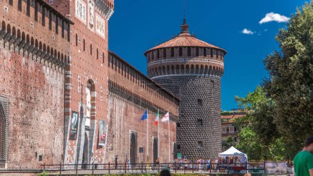 Téléchargez les photos : Entrée principale du château et de la tour de Sforza - Castello Sforzesco timelapse, Milan, Italie. Ciel bleu le jour d'été. Des gens qui se promènent. Vue latérale - en image libre de droit