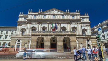 Téléchargez les photos : Salle de concert principale du Teatro alla Scala, un opéra à Milan, Italie. Trafic sur la route. Ciel bleu le jour d'été. Scala est considérée comme l'un des plus grands théâtres d'opéra et de ballet au monde. - en image libre de droit