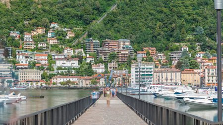 Photo for Landscape with Lake Como timelapse, Lombardy, Italy. People on pier with monument. Houses and boats on background. Cloudy sky at summer day. - Royalty Free Image
