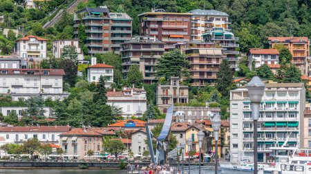 Photo for Landscape with Lake Como timelapse, Lombardy, Italy. People walking on pier with monument. Houses and boats on background. Cloudy sky at summer day. - Royalty Free Image