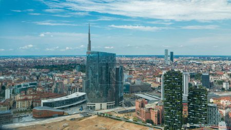 Foto de Vista aérea de Milán de las modernas torres y rascacielos y la estación de tren de Garibaldi en el distrito de negocios timelapse vista desde la azotea. Casas con techos rojos. Cielo azul nublado en el día de verano - Imagen libre de derechos