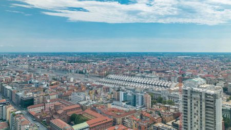 Foto de Milán vista aérea de los edificios residenciales y la estación central de tren en el distrito de negocios timelapse vista desde la azotea. Casas con techos rojos. Cielo azul nublado en el día de verano - Imagen libre de derechos