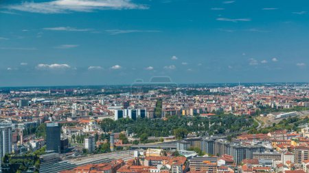 Foto de Vista aérea de Milán de los edificios residenciales y la estación de tren de Garibaldi en el distrito de negocios timelapse vista desde la azotea. Casas con techos rojos. Cielo azul nublado en el día de verano - Imagen libre de derechos