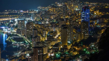 Téléchargez les photos : Vue aérienne panoramique de Monaco depuis la grande corniche route nuit timelapse, Monaco France. Éclairage du soir sur les bâtiments. Trafic sur la route. - en image libre de droit