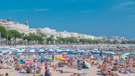 Téléchargez les photos : Bâtiments colorés de la vieille ville et plage de Cannes timelapse sur la Côte d'Azur par une belle journée d'été, France. Mer d'Azur, les gens se détendre sur un sable - en image libre de droit