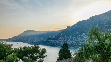 Téléchargez les photos : Paysage urbain timelapse de Monte Carlo, Monaco panorama pendant le coucher du soleil d'été. Rayons de soleil couchant avec brume nocturne. Yachts sur le port. Vue de dessus depuis Cap Martin - en image libre de droit