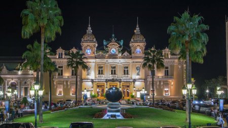 Foto de Grand Casino en Monte Carlo noche timelapse, Mónaco. edificio histórico y plaza frente a él. Vista frontal con entrada. Las palmas al costado. Iluminación nocturna - Imagen libre de derechos