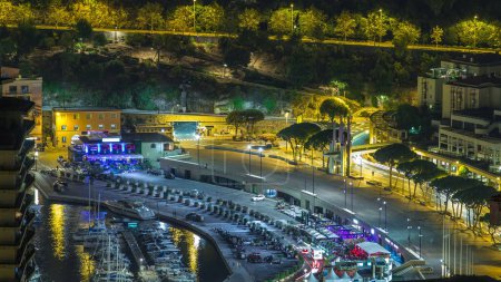 Foto de Paisaje urbano de Montecarlo, Mónaco noche timelapse con yates y el tráfico en el paseo marítimo. Vista aérea desde las colinas. - Imagen libre de derechos
