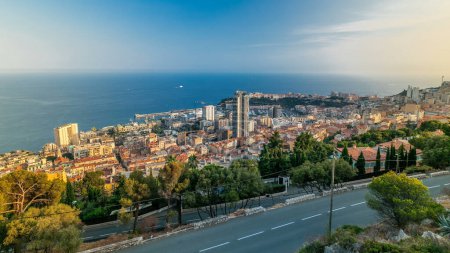 Téléchargez les photos : Paysage urbain panoramique timelapse de Monte Carlo, Monaco avec des toits de bâtiments et de la circulation sur la route pendant le coucher du soleil d'été. Vue aérienne du dessus depuis les collines. - en image libre de droit