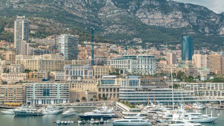 Foto de Cronograma del panorama aéreo de la ciudad de Monte Carlo. Vista de yates de lujo, barcos y hermosos edificios y hoteles en el puerto de Mónaco, Costa Azul. Port Hercule desde la cima con colinas en el fondo - Imagen libre de derechos