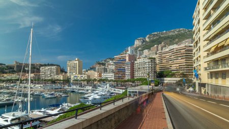 Foto de Monte Carlo Port Hercule hiperlapso de lapso de tiempo panorámico. Vista desde el paseo marítimo con yates de lujo, barcos y casas alrededor del puerto de Mónaco, Costa Azul. Tráfico en la carretera - Imagen libre de derechos