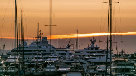 Foto de Hermoso amanecer sobre el puerto de Mónaco timelapse vista de cerca. Los yates de lujo se iluminan con la luz de la mañana. Cielo colorido en el día de verano - Imagen libre de derechos