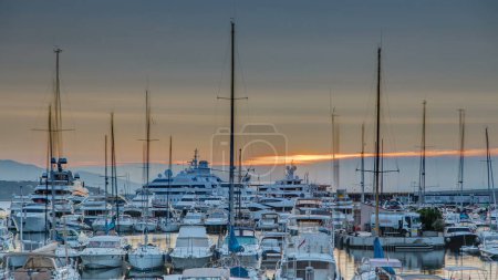 Foto de Hermoso amanecer sobre el puerto en Mónaco timelapse. Los yates de lujo se iluminan con la luz de la mañana. Cielo naranja en el día de verano - Imagen libre de derechos