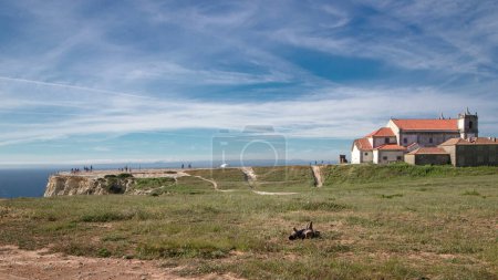 The coastline near cape Espichel, Portugal timelapse with clouds and walking tourists. House on the top of cliff