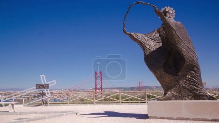 Téléchargez les photos : Le pont 25 de Abril est un pont reliant la ville de Lisbonne à la municipalité d'Almada sur la rive gauche de la rivière Tejo du point de vue avec statue, Lisbonne timelapse - en image libre de droit