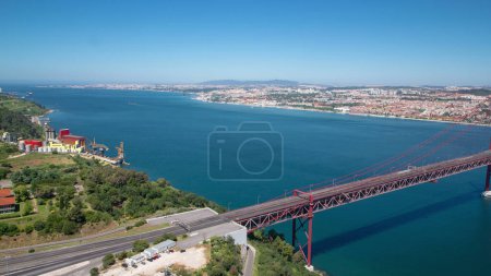 Photo for 25th of April Suspension Bridge over the Tagus river, connecting Almada and Lisbon in Portugal aerial timelapse from above - Royalty Free Image