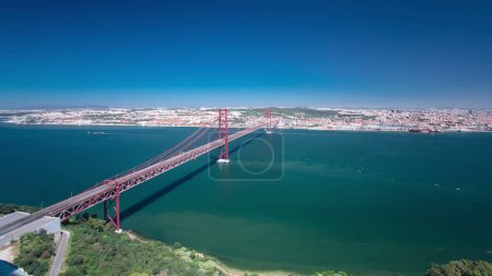 Photo for 25th of April Suspension Bridge over the Tagus river, connecting Almada and Lisbon in Portugal aerial panoramic timelapse - Royalty Free Image