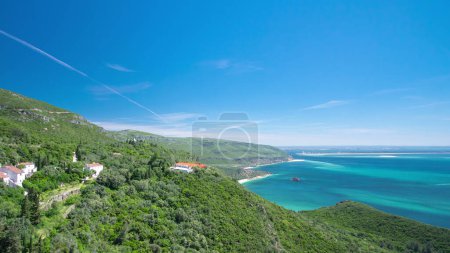 Bahía de la playa en Portinho da Arrabida con agua turquesa y colinas verdes, Portugal timelapse aéreo. Casas en un bosque
