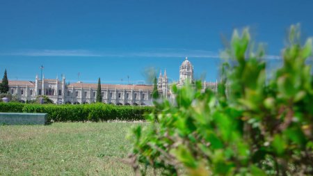 The Jeronimos Monastery or Hieronymites Monastery with green lawn and fountain is located in Lisbon, Portugal timelapse hyperlapse with blue sky